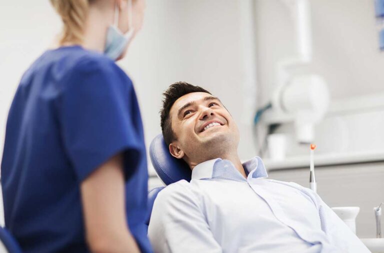 A person sitting in a dentist's chair receiving a dental examination from a provider wearing gloves.