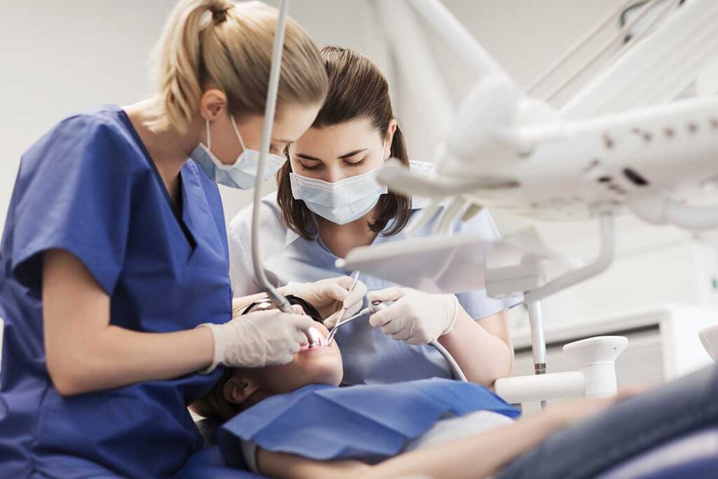 Parent holds a toddler on their lap while a dentist gently examines the child’s first teeth.
